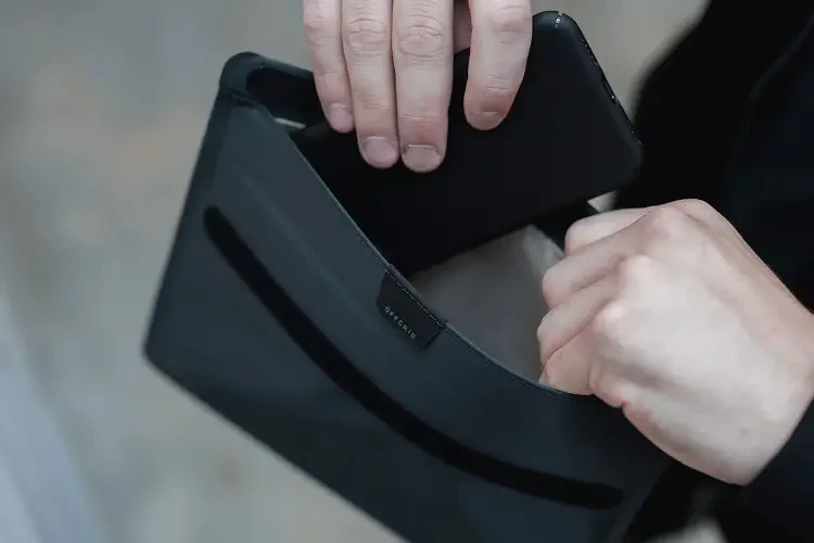 Man putting his cellphone inside Faraday bag